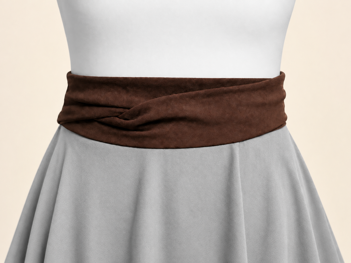 Detalle de las cintas cruzadas de una saya marrón oscuro sobre un maniquí blanco